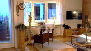 Een woonkamer met een open haard, een televisie en uitzicht op de stad.