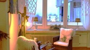 Een knus vertrek met rieten meubels, een radiator en uitzicht door een raam.