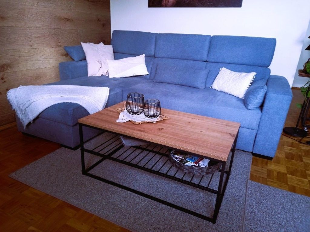 Un salon avec un canapé bleu, une table basse en bois et un tapis gris.
