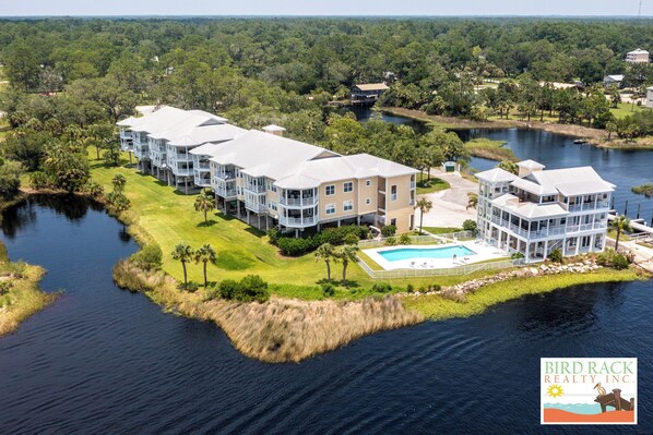A waterfront hotel with multiple buildings, a swimming pool, and a dock.