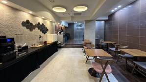 Un restaurante moderno con una barra larga, varias zonas de estar y un lavadero visible al fondo.