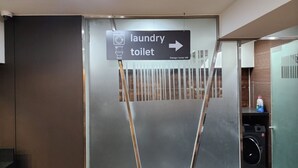 Señal que indica servicios de lavandería y sanitarios, con una lavadora visible al fondo.