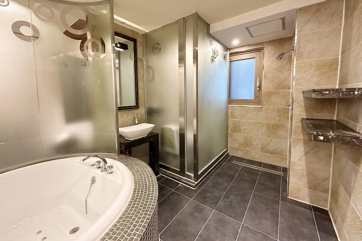 A modern bathroom with a large bathtub, a glass-enclosed shower, and a vanity with a sink.