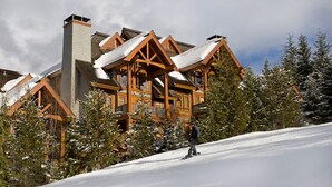 A lodge with a steeply pitched roof, wooden exterior, and snow-covered surroundings. - Mountain townhouse w/ ski access & hot tub (Whistler)