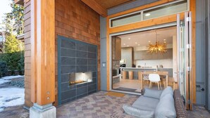 A modern outdoor living area with a fireplace, a dining table, and a sofa. - Lakeside townhouse w/ private garage (Whistler)