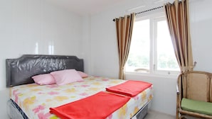 Een slaapkamer met een bed, een stoel en een raam met gordijnen.