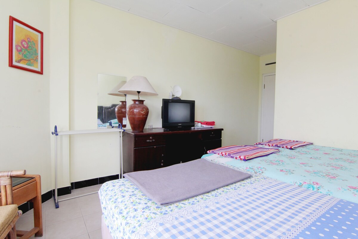 A bedroom with a bed, a dresser, a television, and a lamp.
