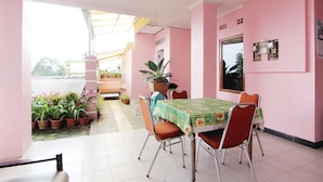 Een kamer met roze wanden, een eettafel met stoelen, een potplant en een raam.