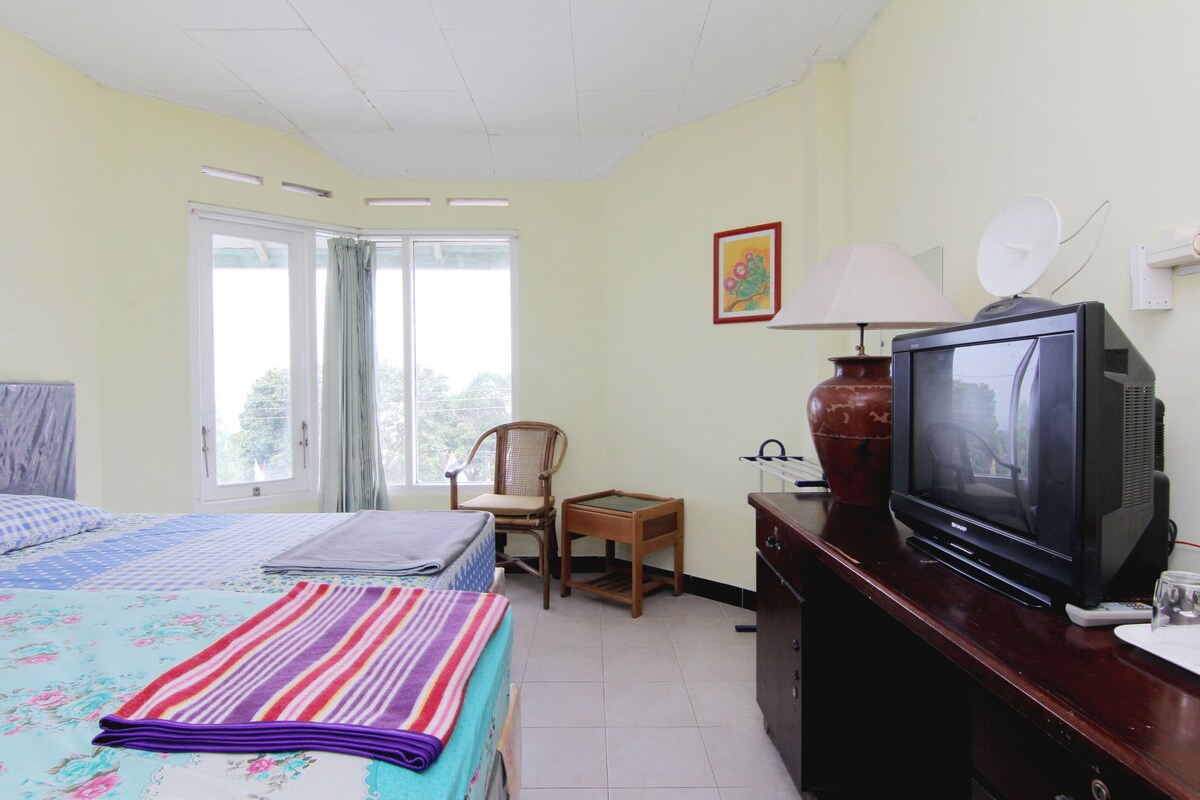 A hotel room with a bed, a television, a chair, a desk, and a window.
