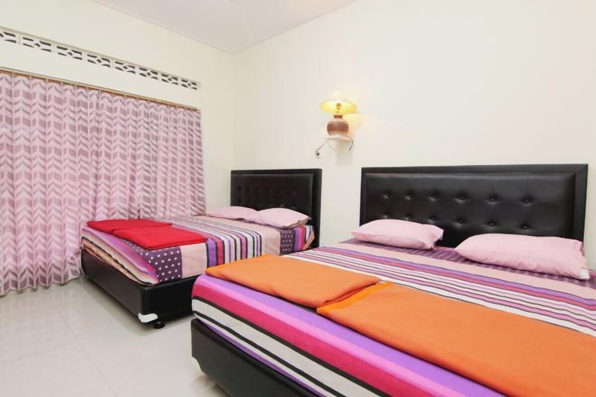 Een slaapkamer met twee bedden, een wandlamp en een kamerbreed gordijn.