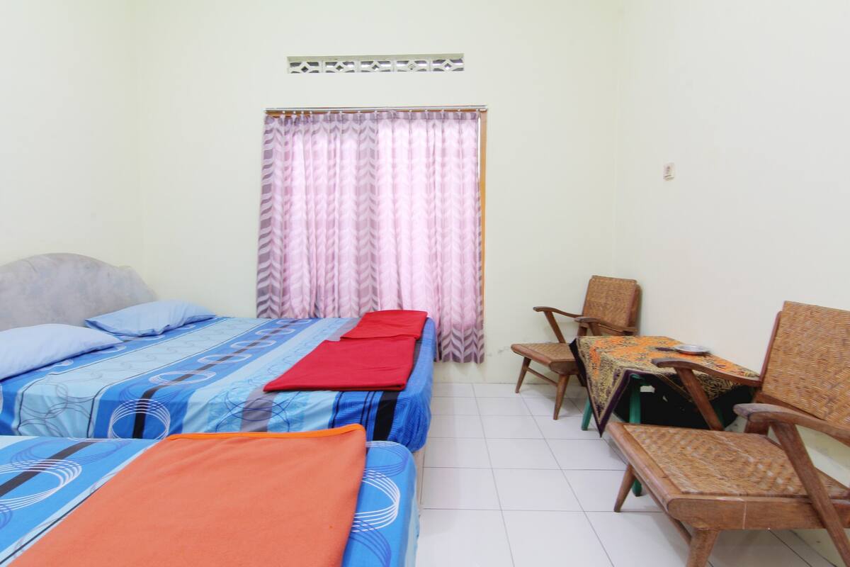 A room with two beds, a small table, and two chairs.
