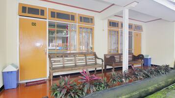 A lobby with wooden benches, a trash bin, and a potted plant arrangement.