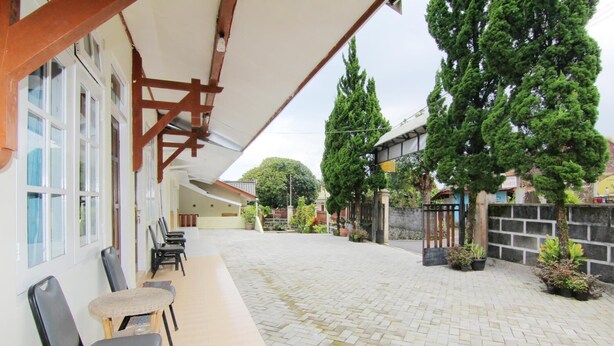 Un espacio al aire libre cubierto con sillas y una mesa, un patio empedrado y un acceso cerrado con plantas en macetas.