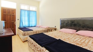 Una habitación con dos camas, una puerta de madera, una mesita y un televisor.