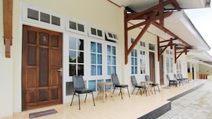 Un edificio con puerta de madera marcada con el número 3, varias ventanas y mobiliario exterior con sillas y mesas.