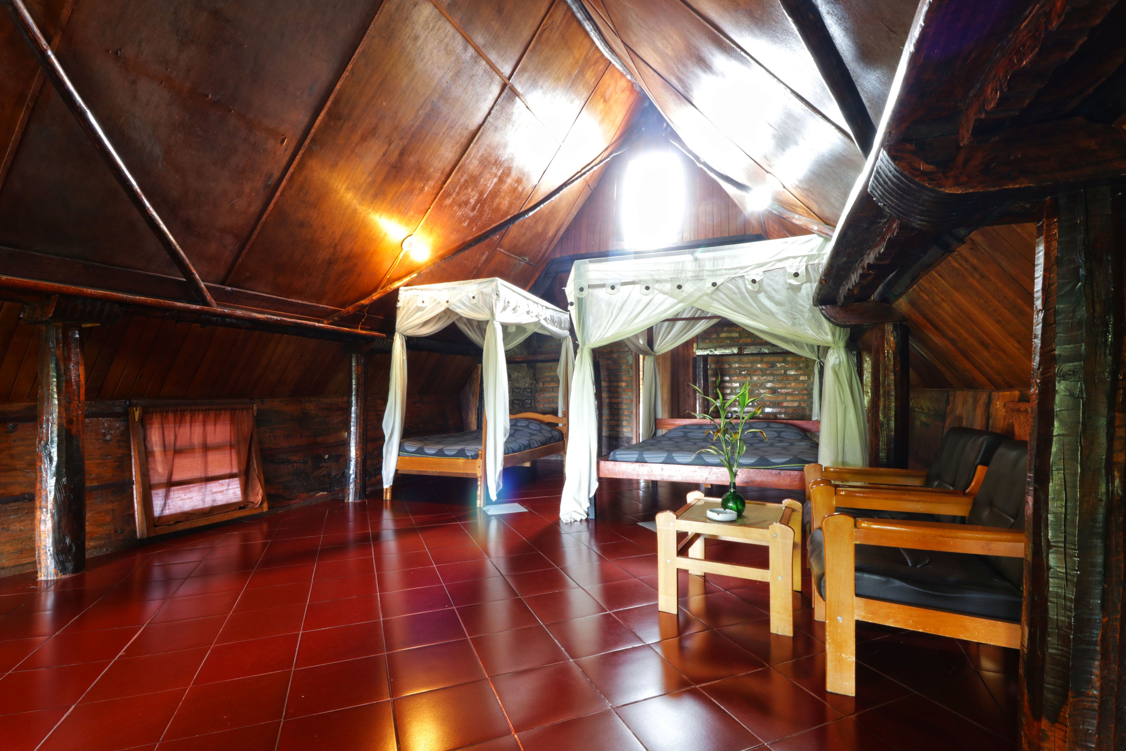 A cozy attic room with a sloped ceiling, wooden floors, and two beds with canopy beds.