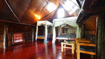 A cozy attic room with a sloped ceiling, wooden floors, and two beds with canopy beds.