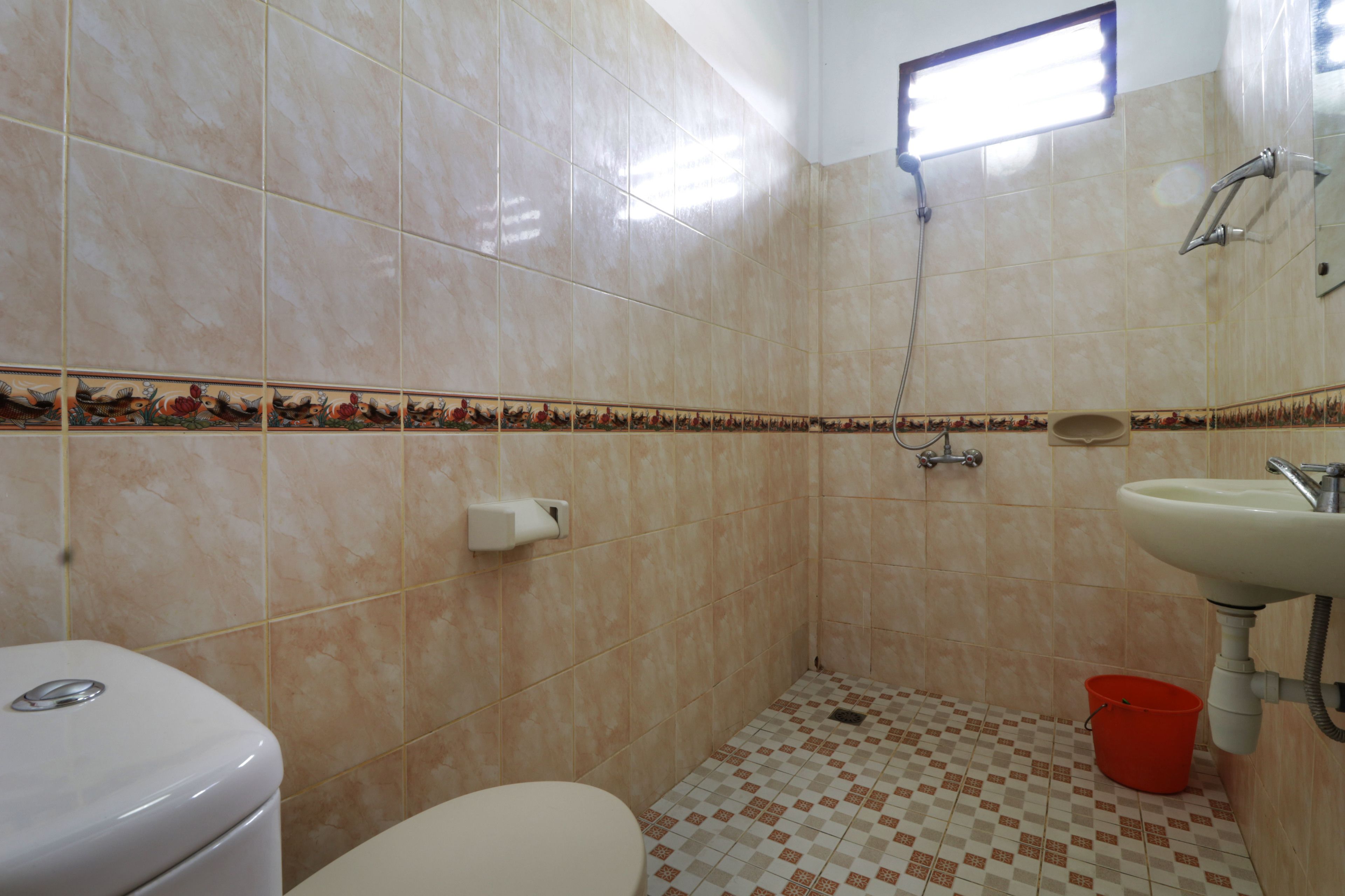 Casa de banho com sanita, lavatório, chuveiro e azulejos decorativos.