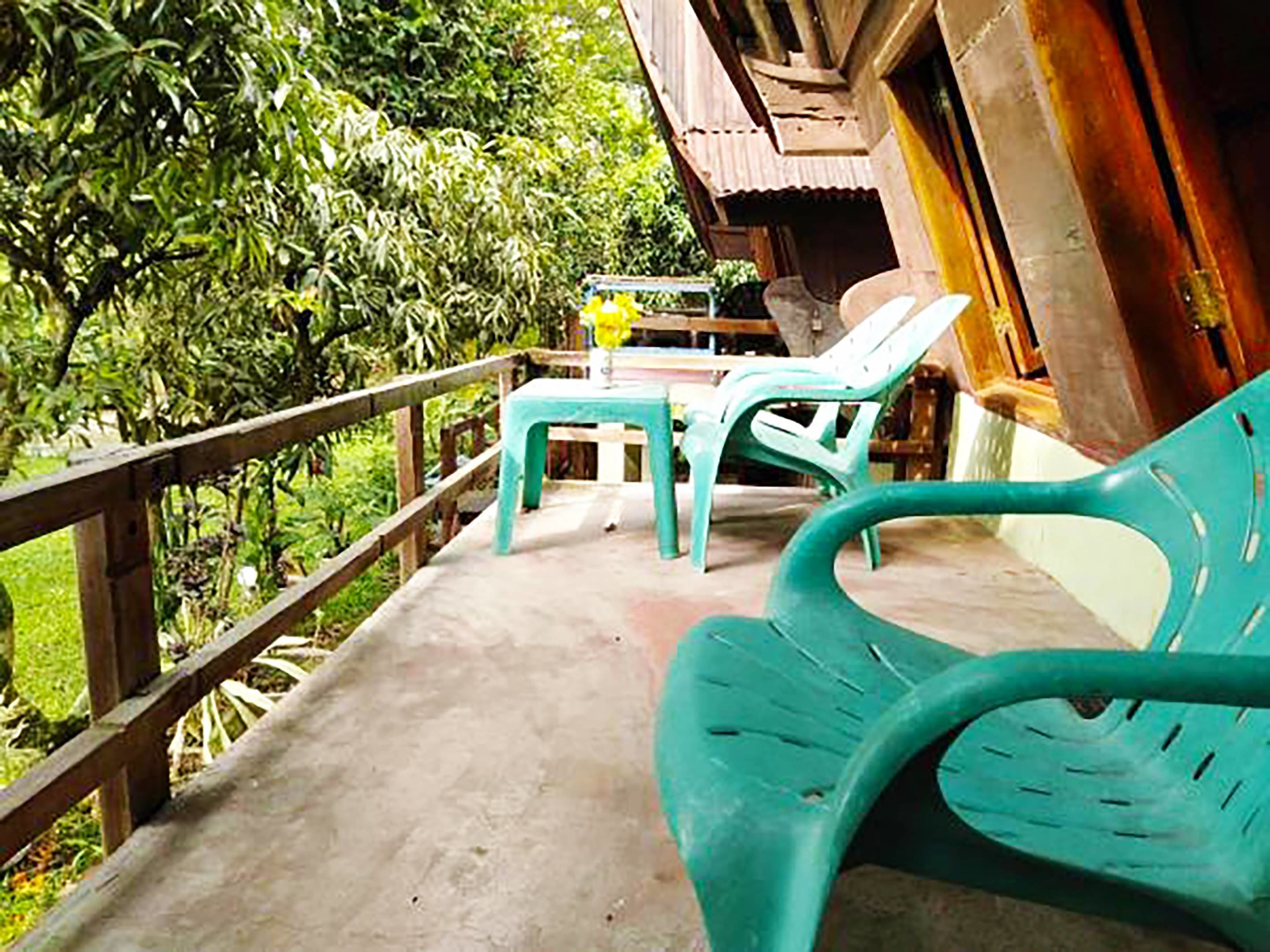 A balcony with a wooden railing, a table with chairs, and a potted plant.
