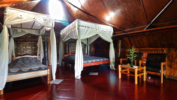 A room with two beds, a small table, and a chair. - Bagus Bay Guest House (Samosir)