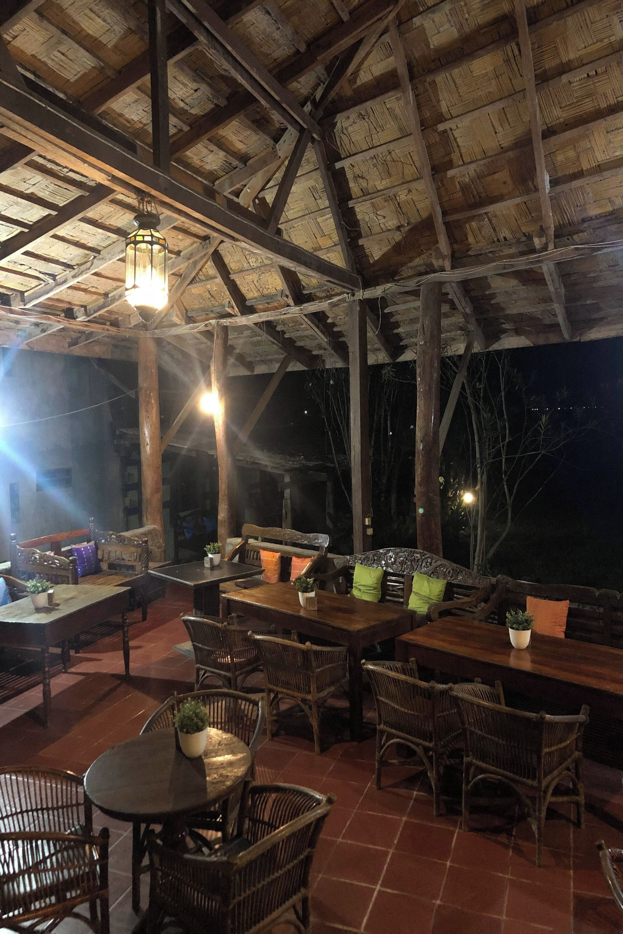 Un espacio de estar al aire libre con muebles de madera y techo de paja.