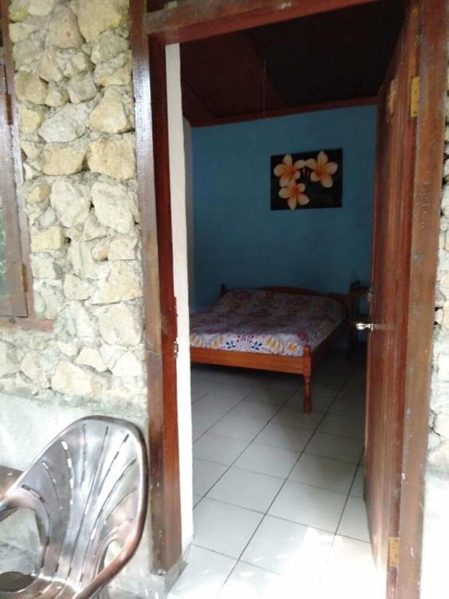 A room with a bed, a chair, and a stone wall.