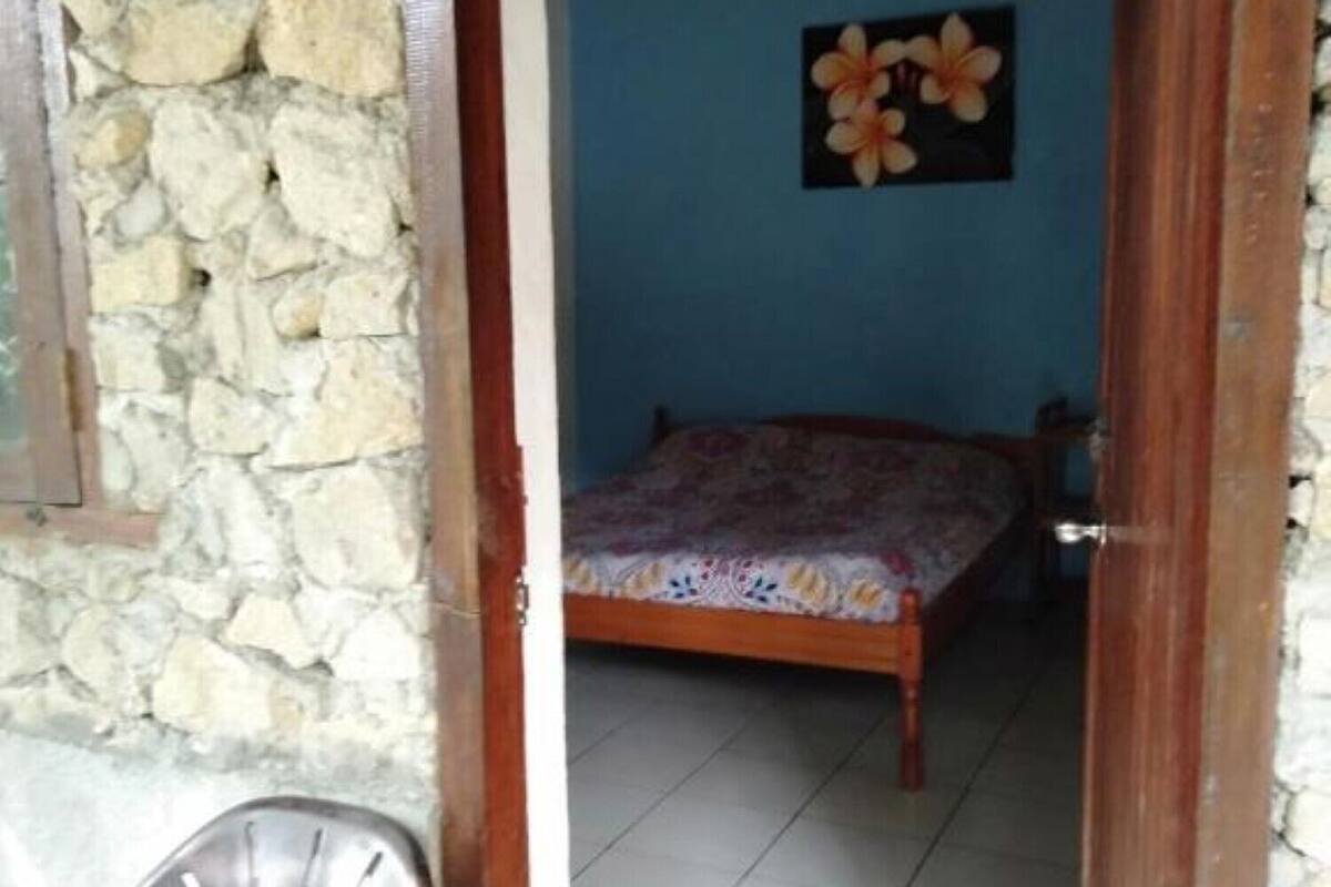 A room with a bed, a chair, and a stone wall.