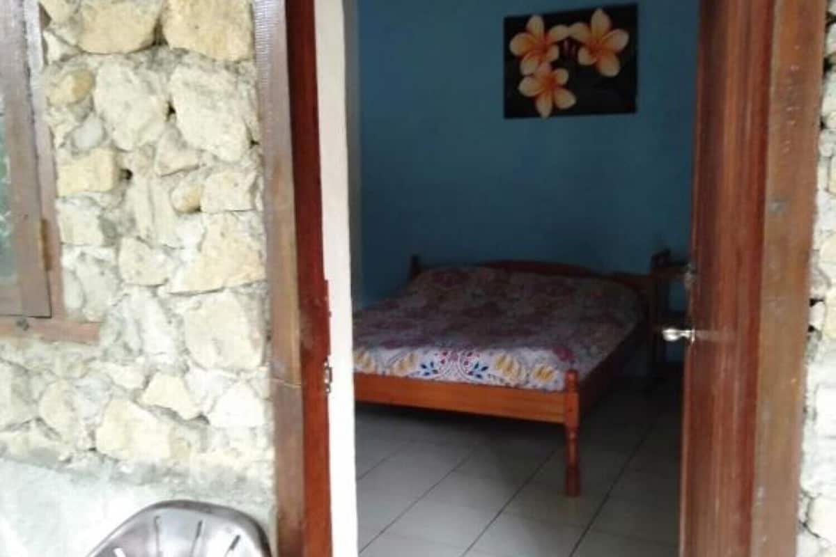 Une pièce avec un lit, une chaise et un mur en pierre.