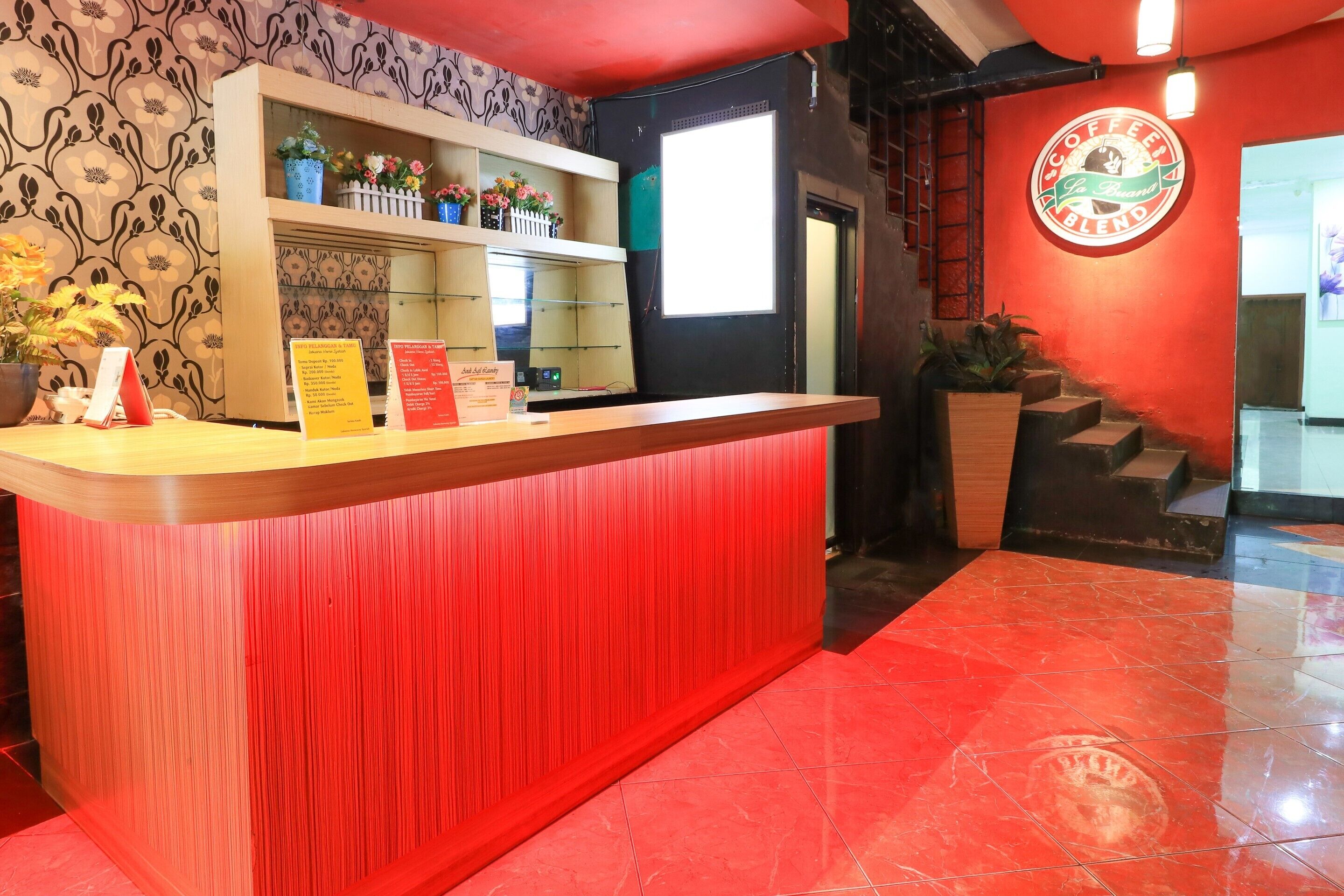 Un mostrador de recepción con una decoración en rojo y blanco, un papel tapiz con estampado floral y un cartel.