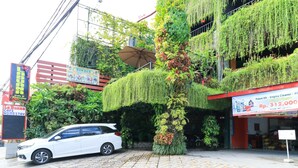 A white car parked in front of a building with a vertical garden and a sign for 'Bukker'. - Labuana Homestay and Cafe Garden Makassar (Makassar)