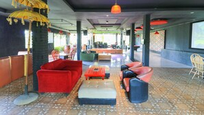 A spacious lounge area with modern furniture, including red sofas and a patterned floor. - Labuana Homestay and Cafe Garden Makassar (Makassar)