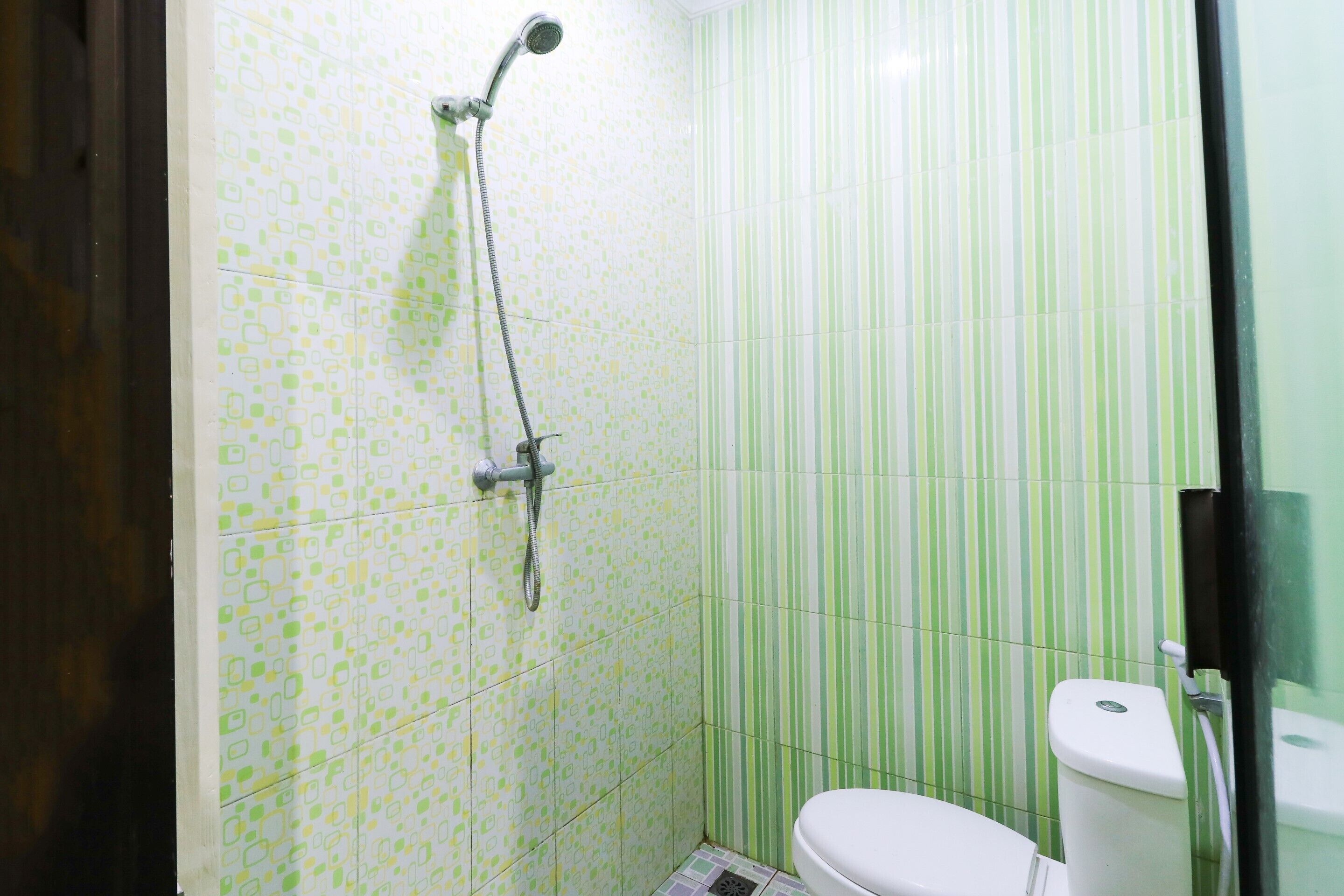 A bathroom with a shower, toilet, and a tiled wall with a geometric pattern.