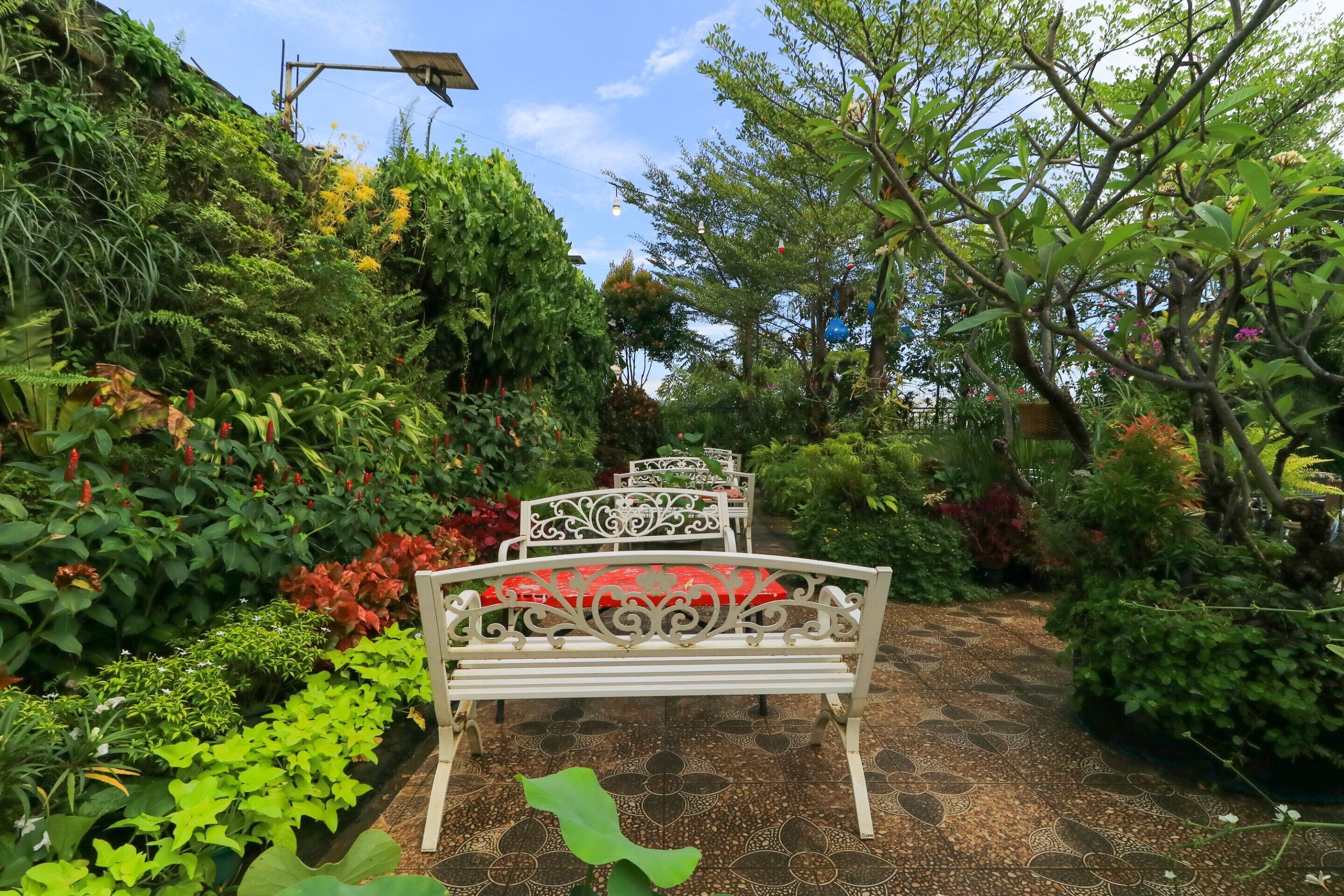 Un jardin avec un banc blanc et un sol à motifs.