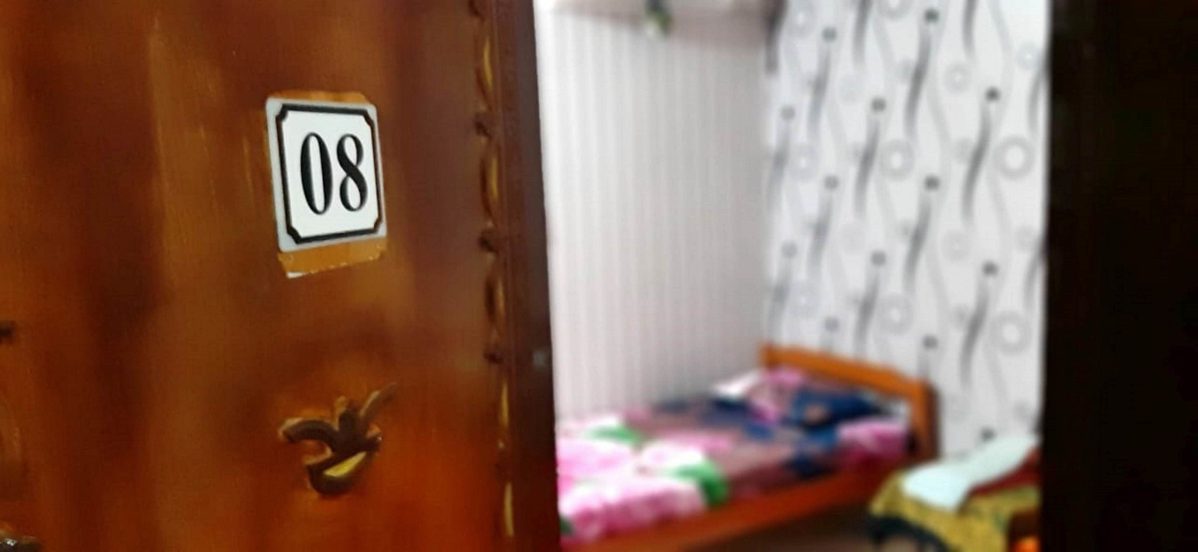 A wooden door with a number '08' sticker and a brass handle.
