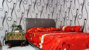 A bedroom with a bed, a nightstand, and a potted plant. - Dharmawati Homestay (Sidoarjo)