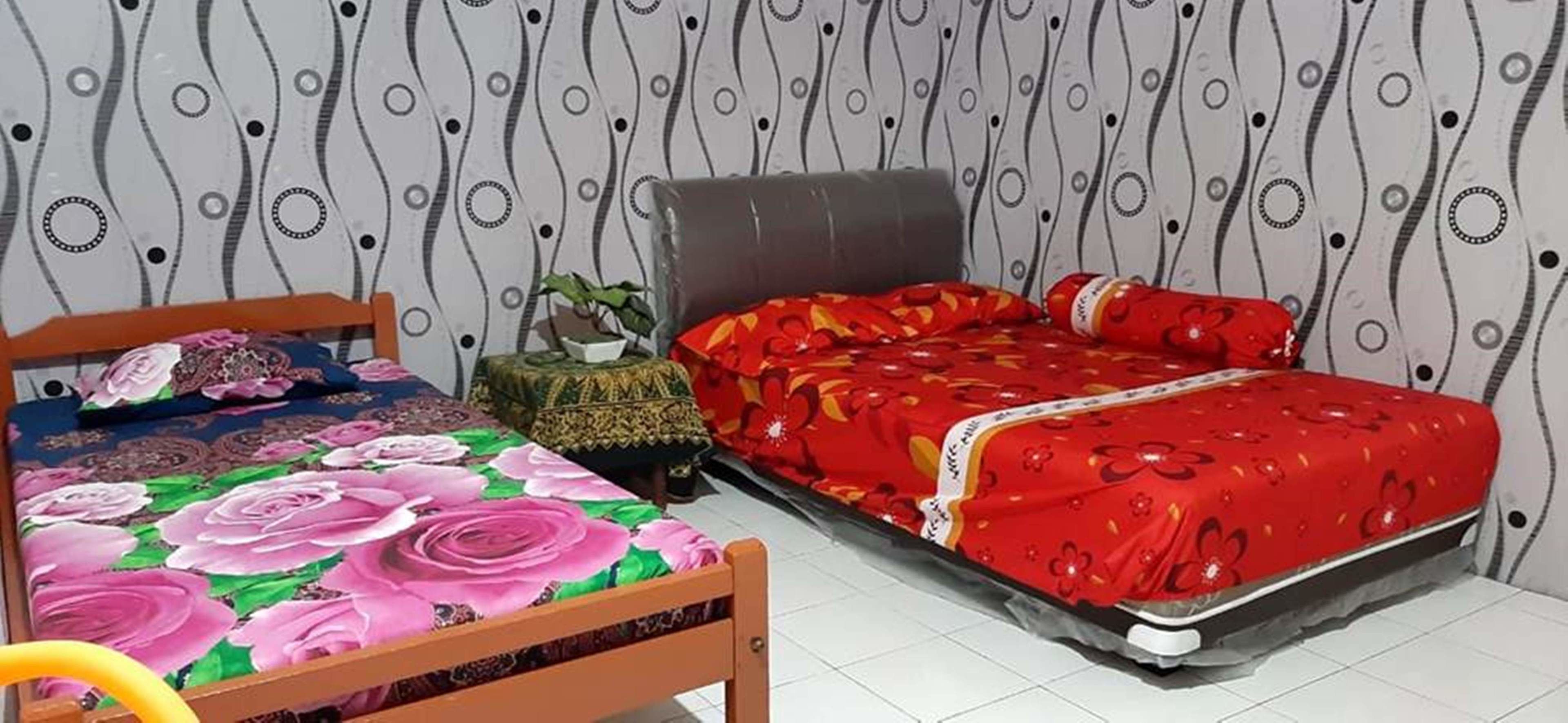 A bedroom with a wooden bed, a small bedside table with a plant, and a patterned wallpaper.
