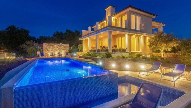 A modern two-story house with a swimming pool and outdoor seating.