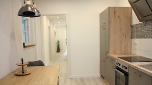A modern kitchen with a wooden table, a black pendant light, and a view into a hallway. - Large, bright vacation apartment in the Lüneburg Heath with pool house and 2 balconies (Oetzen)