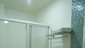 A bathroom with a glass shower enclosure, a toilet, and a sink. - Just Home (Magong)