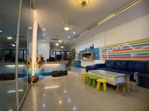 A modern interior with a glass partition, a blue sofa, a glass coffee table, and colorful stools. - Just Home (Magong)
