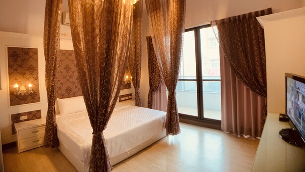 A bedroom with a canopy bed, a TV, and a balcony view. - Just Home (Magong)