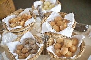 Drie rieten manden gevuld met verschillende gebakken producten, waaronder broodjes en gebak, op een tafel.