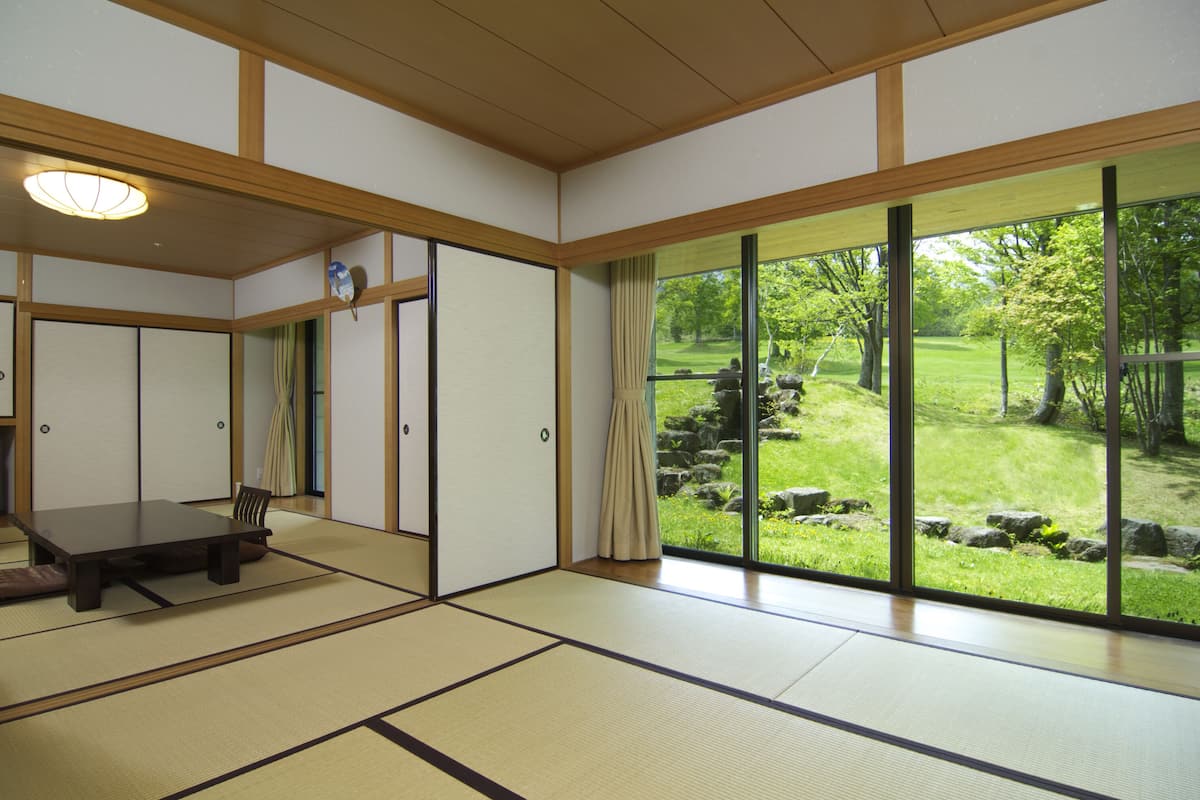 Une pièce de style japonais traditionnel, avec un sol recouvert de tatamis, une table basse et des portes coulissantes.