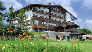 Ein mehrstöckiges Hotel mit Balkonen, einem Restaurant und einer steinernen Fassade.