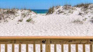 Une plage de sable avec une terrasse en bois au premier plan.