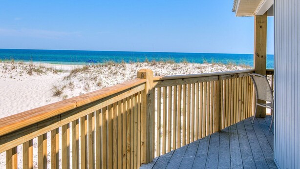 Une terrasse en bois offrant une vue sur la plage et l’océan.