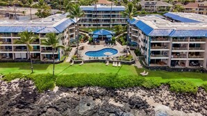 Un hôtel doté d’une piscine centrale, de plusieurs étages et d’un espace paysager aménagé avec des palmiers.