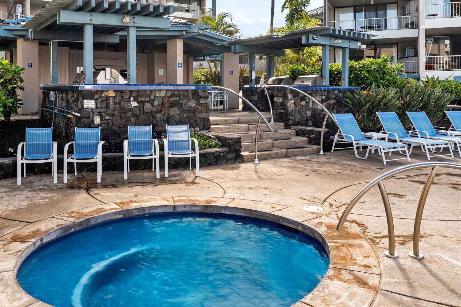 A pool area with a hot tub, lounge chairs, and a stone wall.