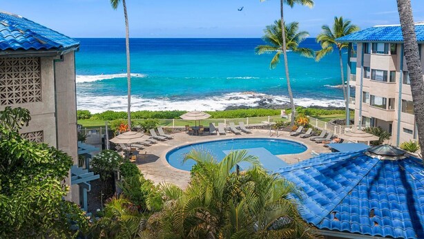 Un complexe hôtelier doté d’une piscine, de chaises longues et offrant une vue sur l’océan.