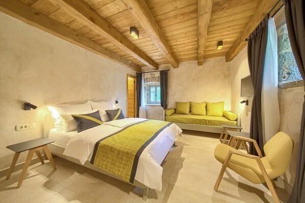A bedroom with a large bed, a sofa bed, a chair, and a small table.